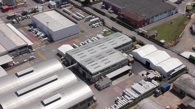Industrial Zone Aerial View: An expansive aerial view showcases a sprawling industrial zone, featuring a complex network of warehouses, factories, and logistical facilities under a clear daytime sky.