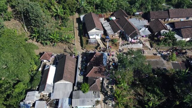 Aerial view of village residents gathering outside traditional houses for a communal festival.