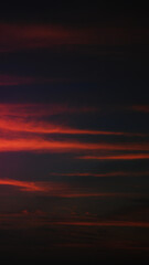 Fototapeta premium Dramatic red and dark clouds during sunset or sunrise in a vertical format