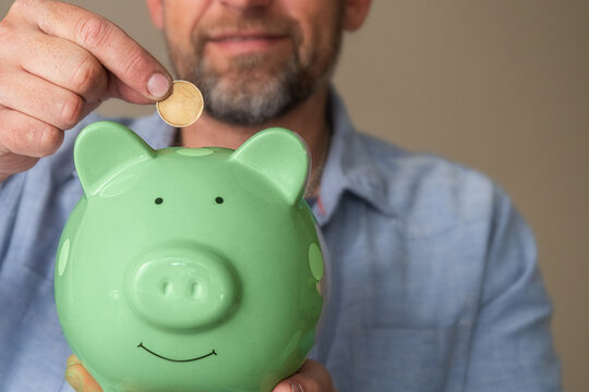 Man Saving Money In Piggy Bank