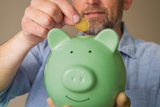 Man Saving Money In Piggy Bank