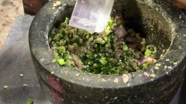 Closeup of Grinding Chilis with a Mortar and Pestle to Make Thai Green Curry Paste
