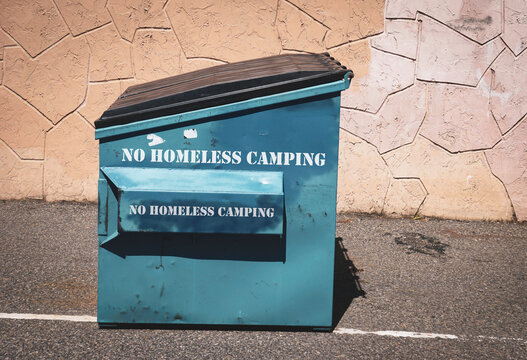 No homeless camping sign on urban trash can in alley