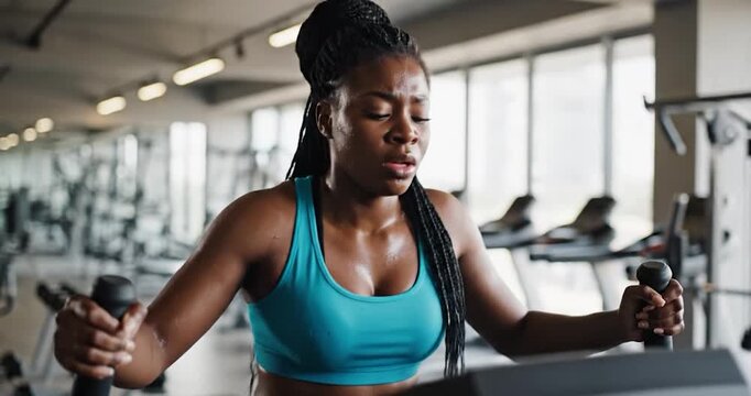 Fit Black Woman Exercising on Elliptical Machine in Modern Gym