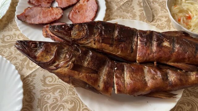 Smoked walleye and pork steaks plated on white plate with patterned tablecloth, golden crispy skin, sliced pork rounds