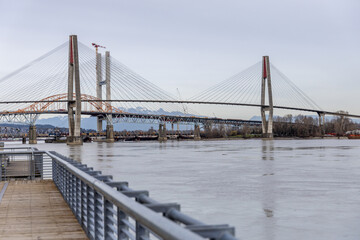 Obraz premium Cable-Stayed Bridge Over River With Waterfront Walkway Near New Westminster, Vancouver, BC, Canada
