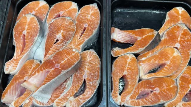 Chilled chum salmon steaks from frozen raw materials on a substrate for sale in a supermarket. Close-up