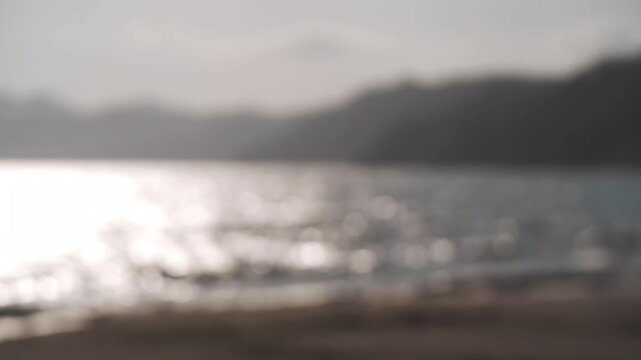 A sandbar at a river mouth flowing into a bay, with the silhouette of distant mountain ranges in the background