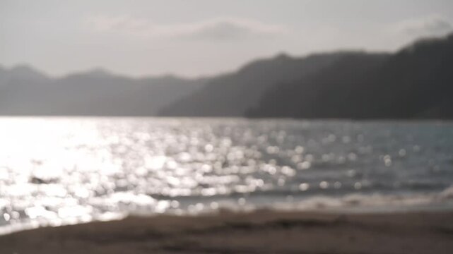 A sandbar at a river mouth flowing into a bay, with the silhouette of distant mountain ranges in the background