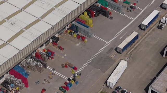 Aerial View of a Busy Logistics Hub: An overhead shot captures a bustling warehouse complex with trucks and containers, illustrating efficient logistics and distribution operations.