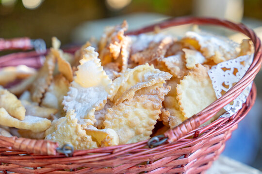 Golden fried pastry pieces with powdered sugar in wicker basket, traditional sweet dessert street food concept.