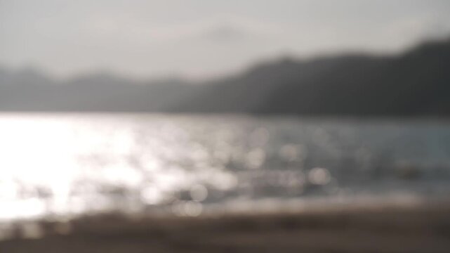 A sandbar at a river mouth flowing into a bay, with the silhouette of distant mountain ranges in the background