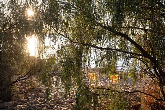 two empty camping chairs sitting on a sandy water front as the sun sets across Lake Pamamaroo, Menidee Lakes, New South Wales, Australia