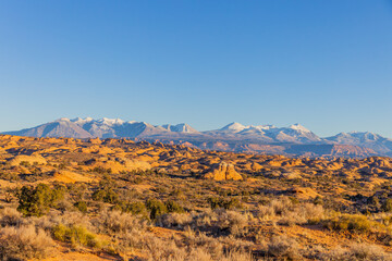 Naklejka premium Snowy mountain peaks stand over a red rock desert landscape