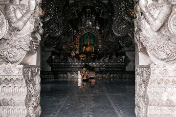 Obraz premium Ornate Buddhist temple interior seen through carved doorway in Chiang Mai, Thailand