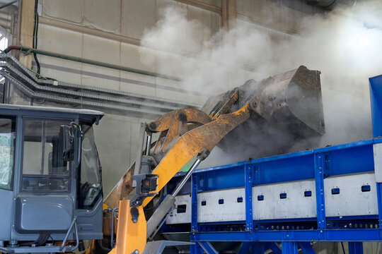 Bucket tractor sorted small fraction waste into a container for further sorting on a conveyor belt for the production of secondary raw materials.
