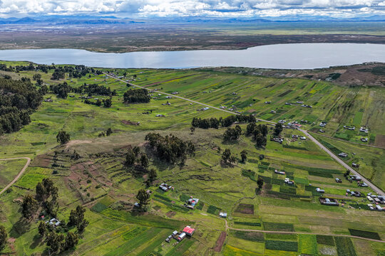 Aerial view of high Andean meadows, small farm plots by a lake