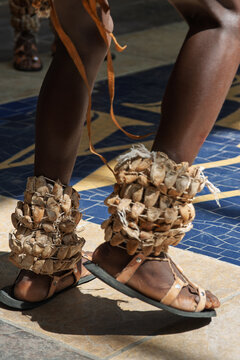 Traditional african dancers wearing leg rattles and woven ornaments during a performance