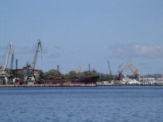 Obraz premium Cargo ship and industrial cranes at the port of Havana Cuba under a blue sky.