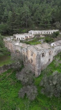 Vertical drone aerial video of Saint Magar Monastery ruins in Northern Cyprus surrounded by mountains and Mediterranean nature.