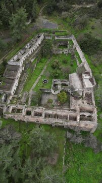 Vertical drone aerial video of Saint Magar Monastery ruins in Northern Cyprus surrounded by mountains and Mediterranean nature.