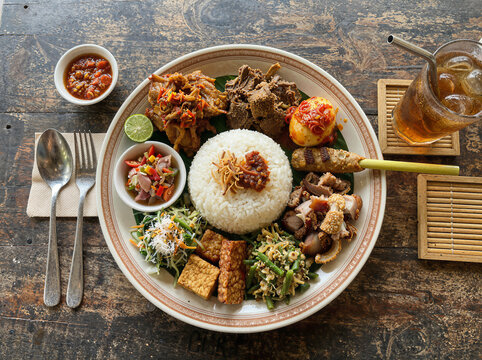 Nasi campur plate rice sambal satay tempeh iced tea rustic table