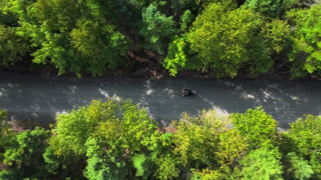 Aerial Top View of cyclists riding through forest near lake in Nova Scotia Canada. Summer nature park landscape with green trees and outdoor activity