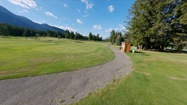 Lush Green Golf Course With Rows Of Parked Golf Carts In Foreground And Scenic Rocky Mountains View. FPV drone shot