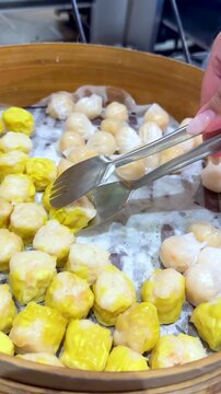 Selecting Fresh Dim Sum Shumai and Har Gow from Bamboo Steamer