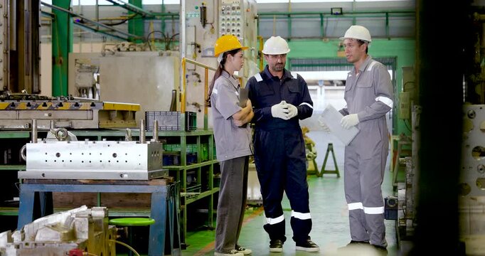 Three adult factory workers review paper document during workshop meeting, supporting technical planning, teamwork communication and production decision making in slow motion