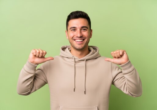 Young man wearing beige hoodie pointing at himself
