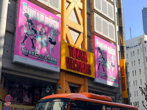 Tower Records Shibuya flagship store exterior with large colorful advertising banners featuring Sugar Rush anime characters on the yellow industrial building facade - Tokyo, Japan, February 21, 2026