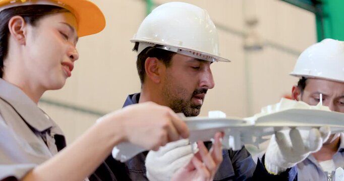 Asian woman engineer and adult male technician examine molded component closely, checking surface detail, fit, safety practice, production standard, quality step inside smart manufacturing workshop.