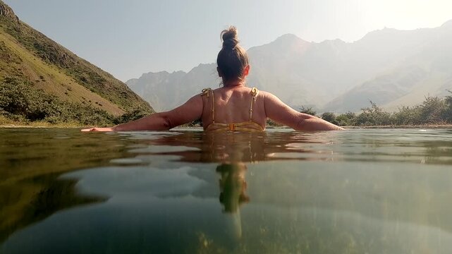 Woman in natural pond with cool mineral water in mountains in morning at sunrise, rejuvenation, harmony with nature