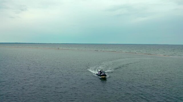 Motor RIB boat traveling across Puck Lagoon near sandbank formation. Aerial view showcases maritime recreation in crystal-clear waters of the region.