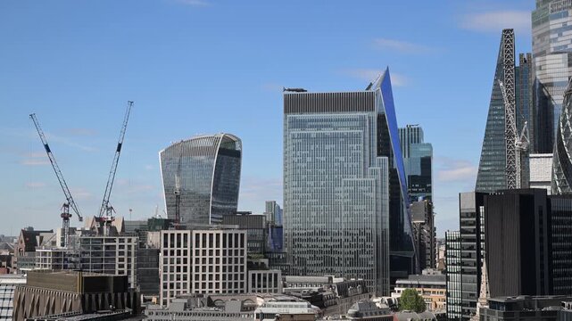A vibrant high-angle view of the London financial district under a clear blue sky, as seen from the modern BT headquarters at One Braham office building
