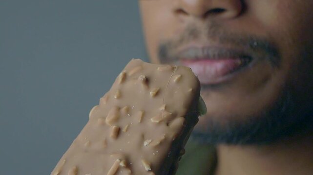 Eating a chocolate treat with nuts on a simple background