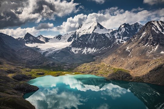 Turquoise mountain lake with snow-capped peaks and glaciers reflecting in the water