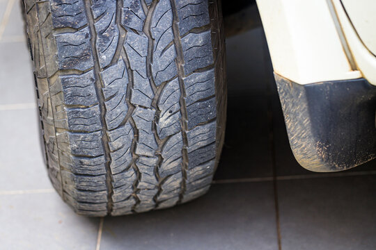 Closeup of a four-wheel drive pickup truck all-terrain tire showing worn tread patterns, dirt, and signs of rugged off-road use