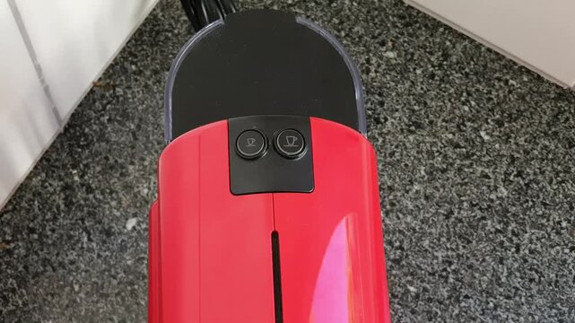 Top view of blinking buttons on red capsule coffee machine warming up.