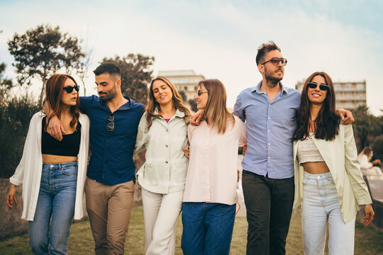 Joyful group of friends enjoying outdoor day with casual camaraderie walking arm in arm