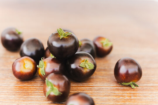 Pile of dark purple Indigo Rose cherry tomatoes on wooden table.