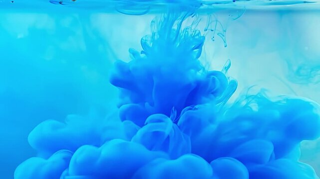 Blue ink dissolving in water, creating abstract swirling shapes and clouds.