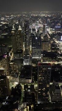 Bangkok skyline at night, downtown cityscape with illuminated skyscrapers and busy traffic lights, cinematic urban atmosphere, modern Thailand metropolis viewed from a high-rise perspective