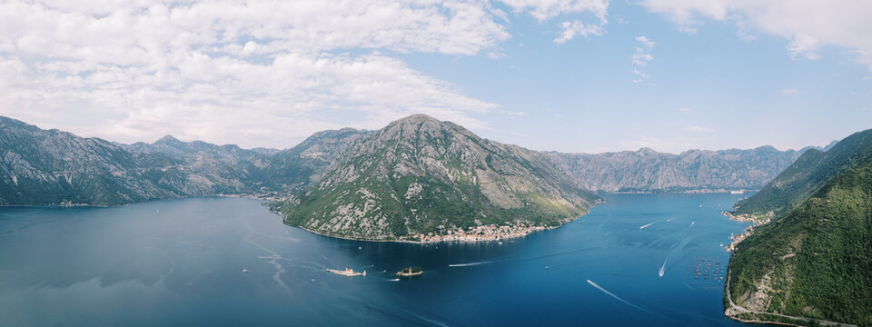 Peaceful island situated near rugged mountain slopes beneath clouds
