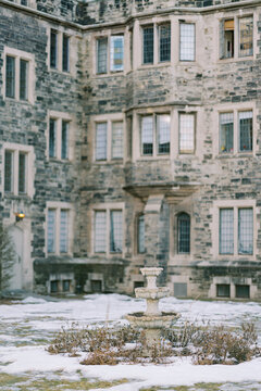 Quiet historic courtyard. Old manor with frosted shrubs and weathered windows. Serene setting with aged stone structures and seasonal frost