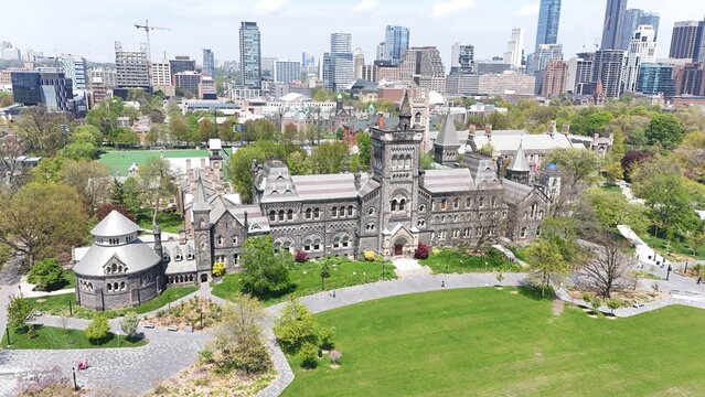 High-angle aerial drone shot of the University of Toronto's historic University College building, featuring the Front Campus lawn, the Croft Chapter House, and the city skyline