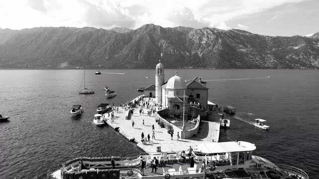 Historic church amid busy harbor. Vibrant Perast island with bustling activities