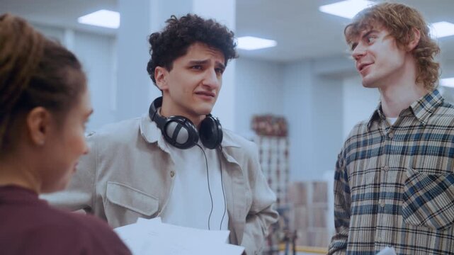 Young male student looking confused and stressed while discussing a difficult assignment with friends