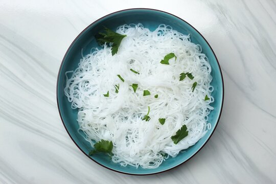 top view of a plate of rice noodles with celery sprinkled on top
